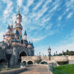 Castle with several towers and an access road where people walk